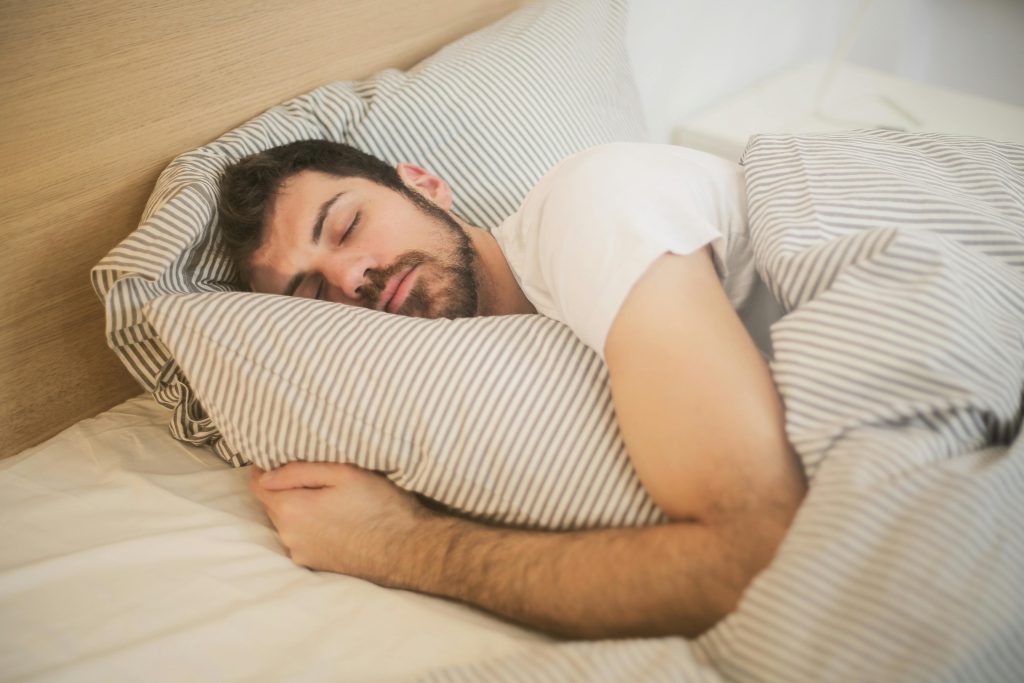 ثرثرة بعد نعاس ثقيل لمحمد الوزاني Man sleeping peacefully on striped bedding, embracing relaxation and comfort.